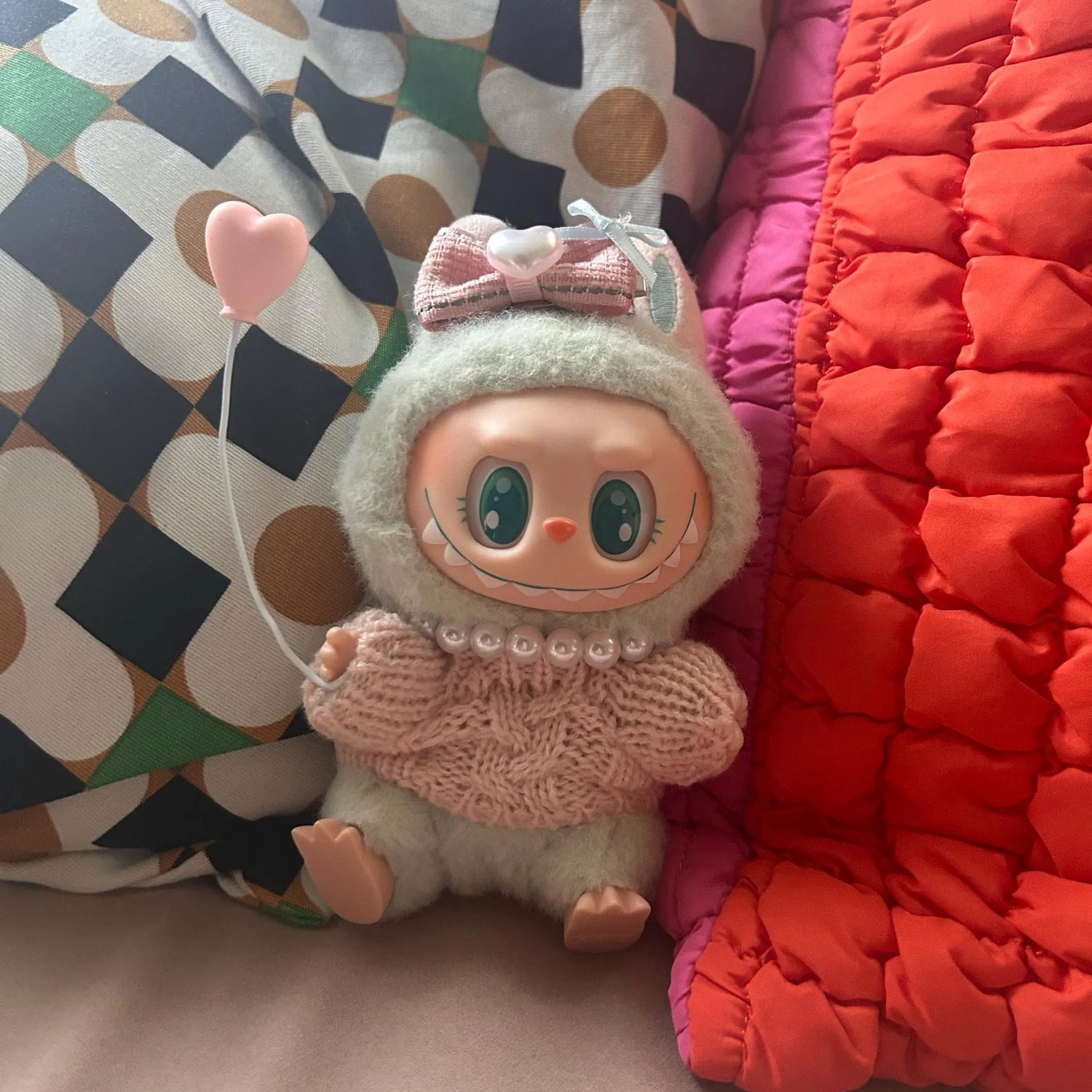 Toy figure with a pink bow and heart-shaped balloon on a colorful background