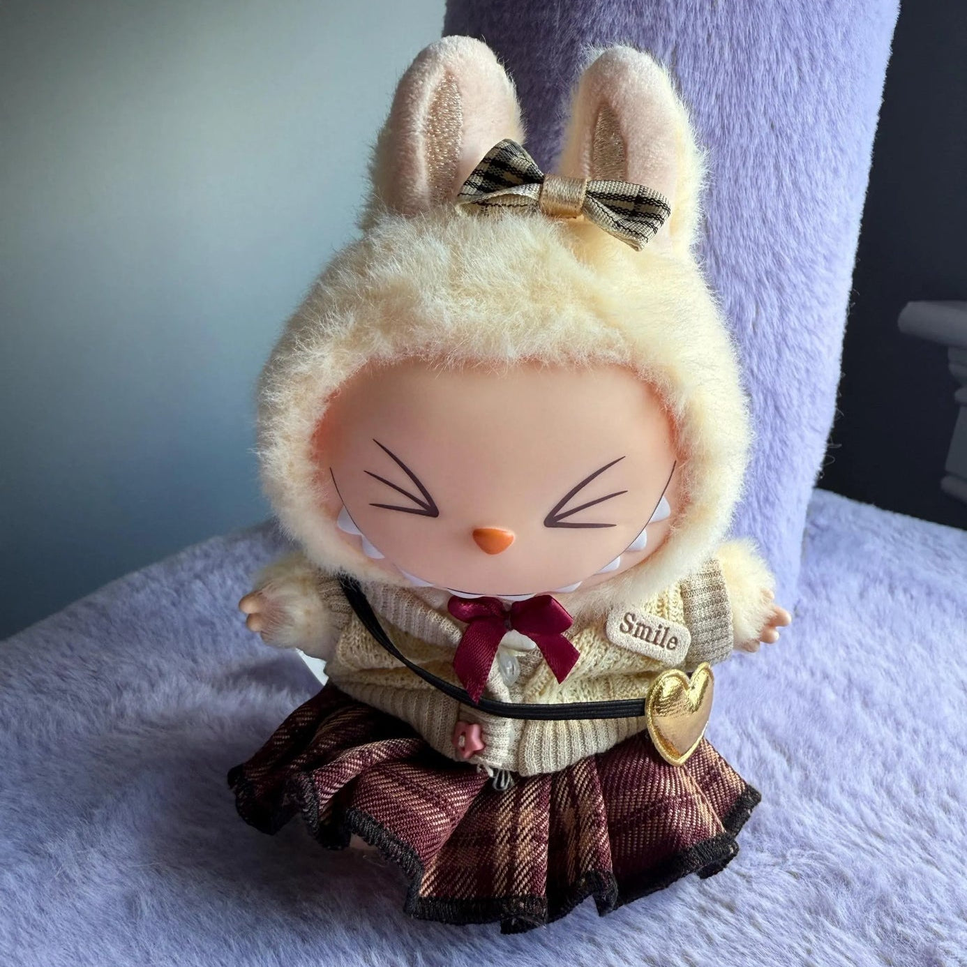 Toy figure of a character with bunny ears and a bow, sitting on a textured surface.